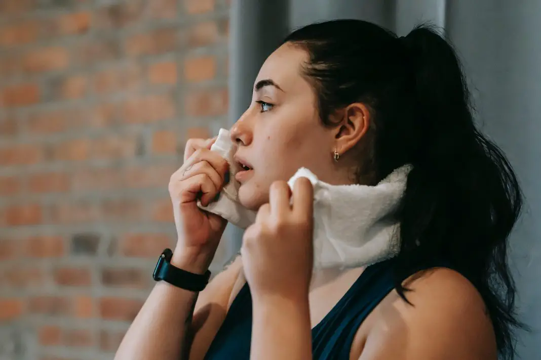 女子在健身房用毛巾擦拭脸上的汗水孔侑dF4y2Ba