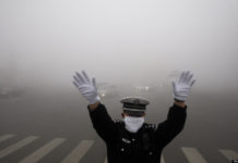 2013年10月21日，中国东北黑龙江省哈尔滨市，一名警察在雾霾弥漫的街道上工作。报道称，令人窒息的污染云团笼罩着以年度冰雪节而闻名的哈尔滨，将能见度降低到10米(33英尺)，凸显了国家的环境挑战。法新社图片(图片来源应为STR/AFP/Getty Images)