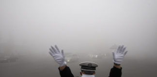 一个警察手势在浓雾笼罩的街道工作在哈尔滨,中国东北的黑龙江省,2013年10月21日。窒息的污染云覆盖哈尔滨一年一度的冰雪节闻名,报道称,削减能见度10米(33英尺),强调国家的环境挑战。中国法新社图片(图片来源应该读STR /法新社/盖蒂图片社)